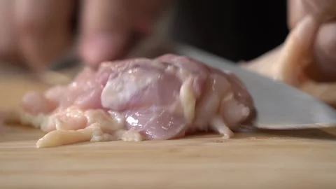 Chef Slicing Uncooked Chicken Meat on a Chopping Board Stock Footage 296523338
