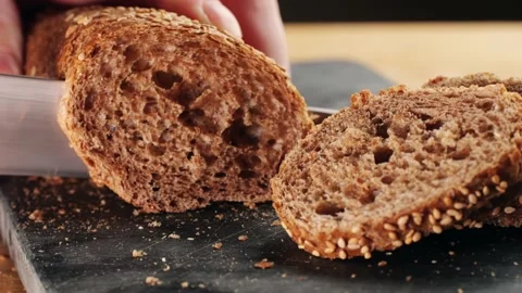 Chef slicing Whole grain bread close-up on the wooden cutting board. Man cutting Stock Footage 232804357