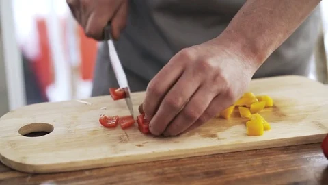 Chef slicing a yellow and red bell peppers and putting them in a bowl 動画素材 76591011