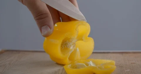 Chef is slicing yellow bell pepper on the wooden board, cutting vegetables Stock Footage 120384898