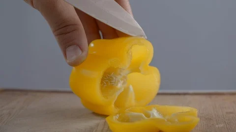 Chef is slicing yellow bell pepper on the wooden board, cutting vegetables Video stock 120533796