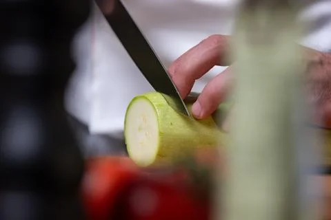 Chef Slicing Zucchini in Kitchen Stock Photos