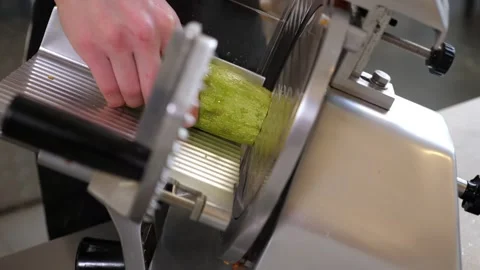 A chef slicing zucchini into thin slices using an industrial slicer. Stock Footage 308001438
