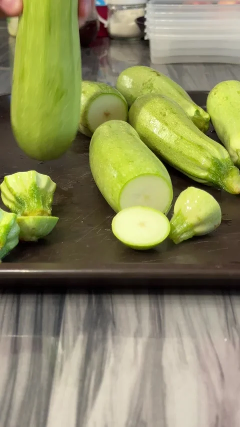 Chef slicing zucchini while preparing a dish in the kitchen, showcasing the c Stock Footage 303358636