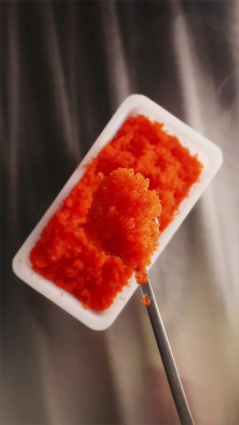 Chef spooning bright orange tobiko flying fish roe from container Stock Footage 337119129
