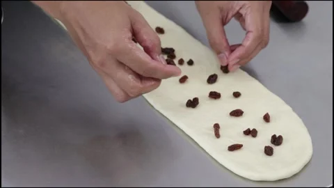Chef spread dried raisin on the loaf dough Stock Footage 296045862