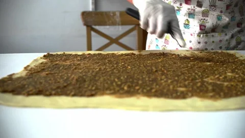 Chef is spreading the cinnamon mixture on the dough. Stock Footage 159737346