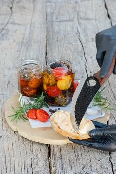 Chef spreading marinated cheese on toasted bread with cherry tomatoes and r.. Stock Photos