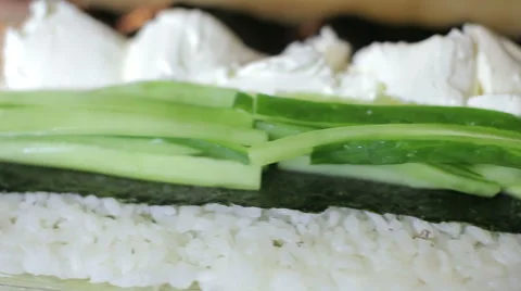 Chef spreading nori and puts cucumber while cooking sushi rolls Stock Footage 62933101