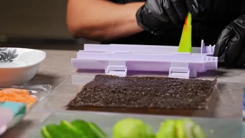 Chef spreading rice on nori sheet using sushi machine Stock Footage 289540579