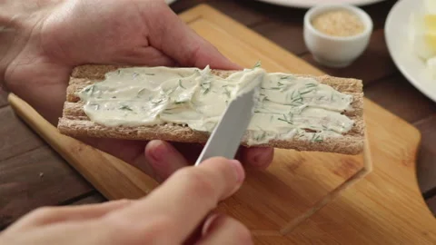 Chef spreading soft cream cheese on crisp bread making healthy sandwich close up Stock Footage 122198620