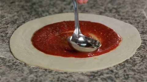Chef spreading tomato sauce on pizza dough with metal ladle in pizza restaurant Stock Footage 73000516