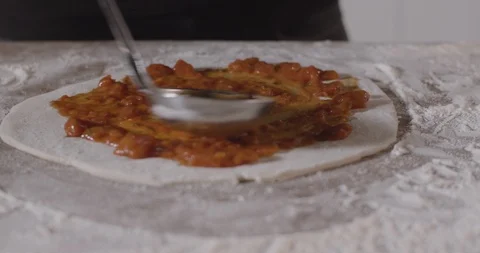 Chef spreading tomato sauce on pizza dough with metal ladle in pizza restaurant. Stock Footage 124875616