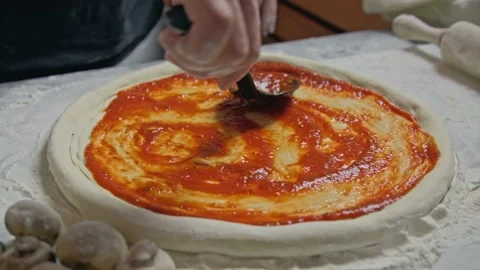 Chef is spreading tomato sauce on pizza dough. Cooker making pizza with a Stock Footage 153036749