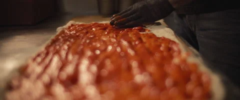 Chef spreading traditional tomato sauce over a fresh pizza al taglio dough Stock Footage 146602774