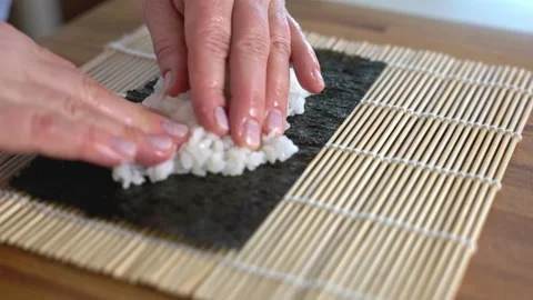 Chef spreading white rice on nori seaweed sheet for sushi. Vidéo 337434516