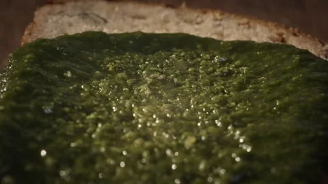 Chef spreads green pesto on a slice of dark bread. footage 50 fps. Stock Footage 301083583