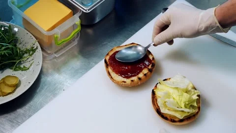 Chef spreads the red sauce with a spoon on a bun. Stock Footage 158644577