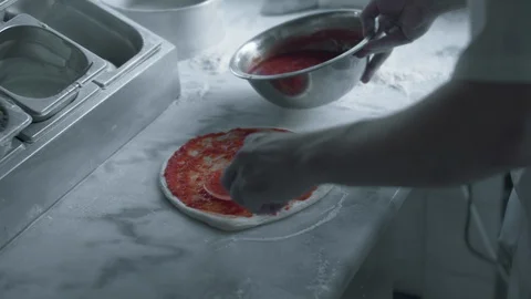 Chef spreads tomato paste and cheese on pizza dough Stock Footage 120802903