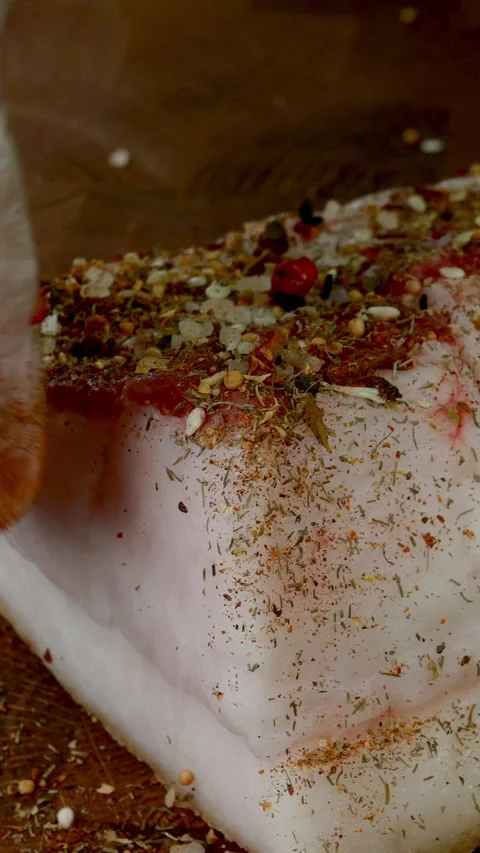 Chef sprinkle piece raw pork lard on wooden kitchen board with spices and salt. Stock Footage 234533122