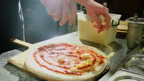 Chef sprinkles cheese cubes spreading topping across sauce ring Stock Footage 325070635