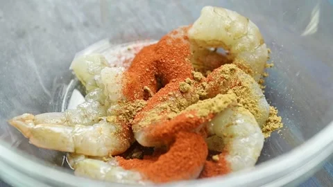 The chef sprinkles cumin over the shrimp in a glass bowl. Video stock 234892577