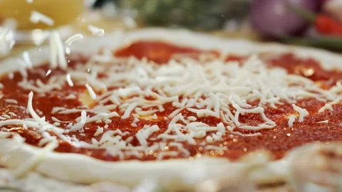 Chef sprinkles fresh mozzarella cheese over pizza dough with tomato sauce i.. Stock Footage 337523019