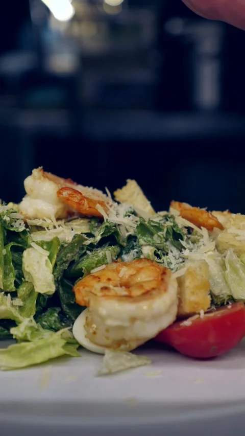 Chef sprinkles grated cheese, parmesan Caesar salad with shrimp. close-up Stock Footage 308826036