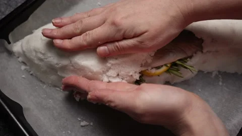 The chef sprinkles large amounts of salt on fresh fish with spices before baking Stock Footage 233356309