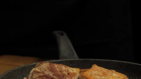 Chef sprinkles salt on roasted meat in a pan close-up Video stock 107724048