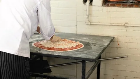 Chef sprinkling cheese to make a pizza in kitchen Stock Footage 153683157