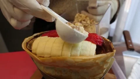 Chef Sprinkling Crushed Nuts on Fresh Banana and Strawberry Crepe Stock Footage 345692173