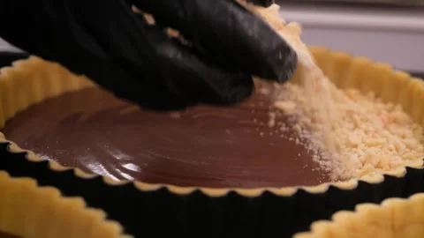 Chef sprinkling golden cookie crumbles on a rich chocolate tart Stock Footage 337751454