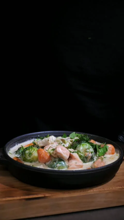Chef sprinkling herbs on vegetables with salmon in a frying pan.  Slow motion Stock Footage 309463519