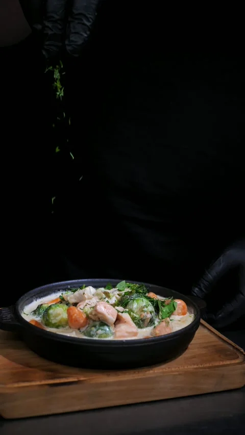 Chef sprinkling herbs on vegetables with salmon in a frying pan.  Slow motion Stock Footage 309463559