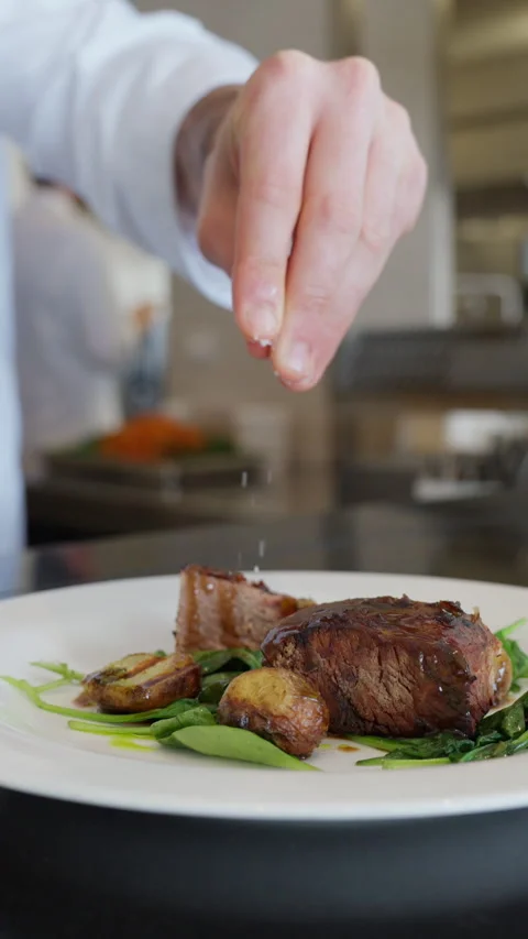 Chef Sprinkling Salt Over Plated Meat Stock-Footage 332232888