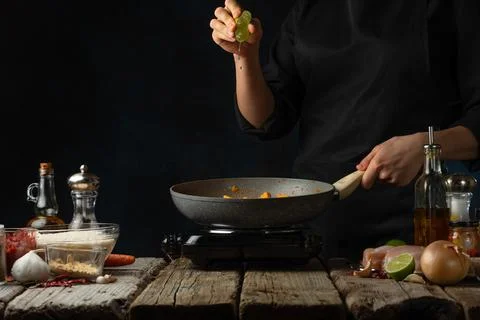 Chef squeeze lime juice into pan with frying chicken fillet. Backstage of coo Stock Photos