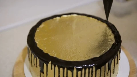 Chef squeezes cream. Chocolate icing on the golden covered cake Stock Footage 106283977