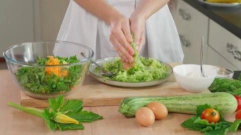 The chef squeezes grated zucchini from the liquid, wooden table Stock Footage 270149888