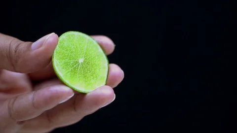 Chef squeezes a lemon in a black background. Stock Footage 99656824