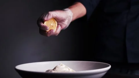 Chef squeezes lemon into white cream on a black background Vídeo Stock 159057913