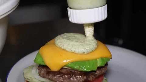 Chef Squeezing Green Sauce onto a Cheeseburger in Close-Up 스톡 동영상 347687785