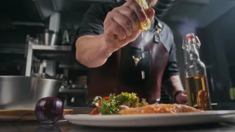 Chef squeezing juice from half a lemon on steak Stock Footage 314755533