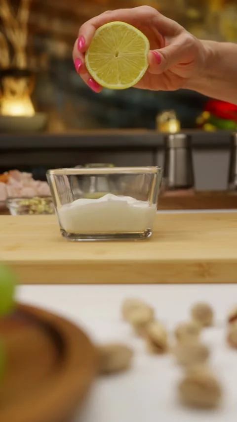 Chef squeezing lemon juice into yogurt sauce for healthy meal preparation Stock Footage 310928587