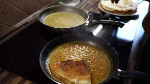 Chef stacks folded pancakes in a frying pan with simmering sweet sauce Stock Footage 269593406