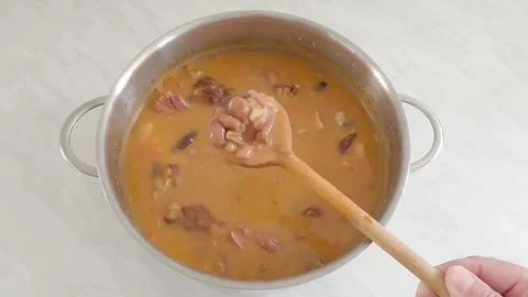 Chef stirring and checking hot meal in the pot with wooden spoon Stock Footage 270205442