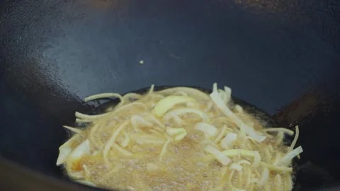 Chef stirring boiling onions in oil in large cauldron for pilaf, close-up Stock Footage 346586017