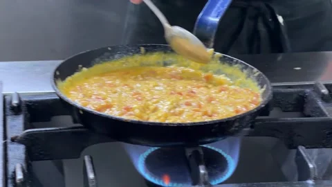Chef stirring creamy scrambled eggs in a pan Stock-Footage 344100175