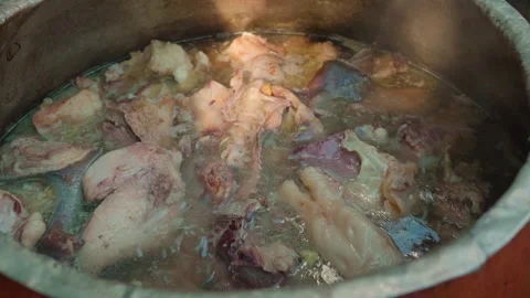 Chef stirring large chunks of meat for plov in a boiling traditional cauldron Stock Footage 346605570