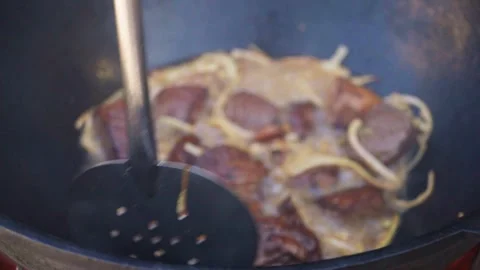 Chef stirring meat and onions frying in hot oil in large kazan for pilaf Stock Footage 346585051